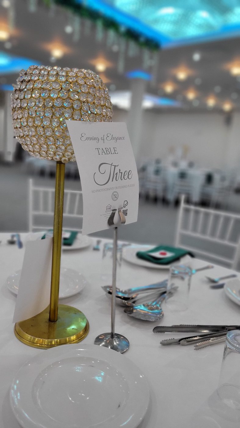 Table set with silverware, napkin and golden table feature with table number three on a stand
